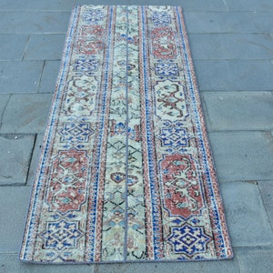 Puede incluir: Una alfombra de pasillo vintage con un diseño persa tradicional. La alfombra tiene un fondo crema con acentos rojos, azules y blancos. La alfombra mide aproximadamente 76 cm de ancho y 244 cm de largo.