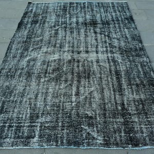 Puede incluir: Una alfombra rectangular desgastada en blanco y negro. La alfombra tiene un aspecto descolorido y vintage con una superficie texturizada. Los bordes están acabados con un ribete azul claro. Adecuado para la decoración del hogar. Medidas en centímetros.