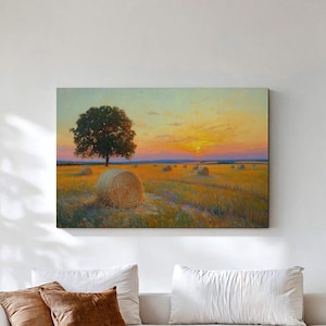 May include: A rectangular landscape painting featuring a golden wheat field with scattered hay bales under a sunset sky. A single large tree stands prominently in the middle ground. The artwork displays warm yellow, orange, and blue hues.