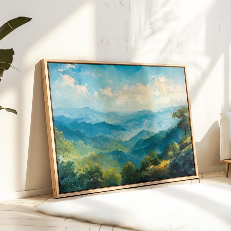 Puede incluir: Pintura de paisaje enmarcada que representa una cordillera bajo un cielo azul con nubes blancas. La obra de arte presenta tonos de azul y verde, con un marco de madera clara. La pintura est&aacute; apoyada contra una pared blanca.
