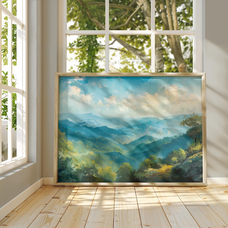 Puede incluir: Una pintura de paisaje enmarcada representa una cordillera bajo un cielo azul brillante con nubes blancas y esponjosas. La obra de arte presenta tonos de azul, verde y amarillo, con un marco dorado. La pintura se exhibe cerca de una ventana.