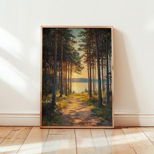 May include: Framed art print showing a path through a forest of tall trees. The artwork features a warm colour palette with a sunset over a lake in the distance. The print is in a wooden frame.