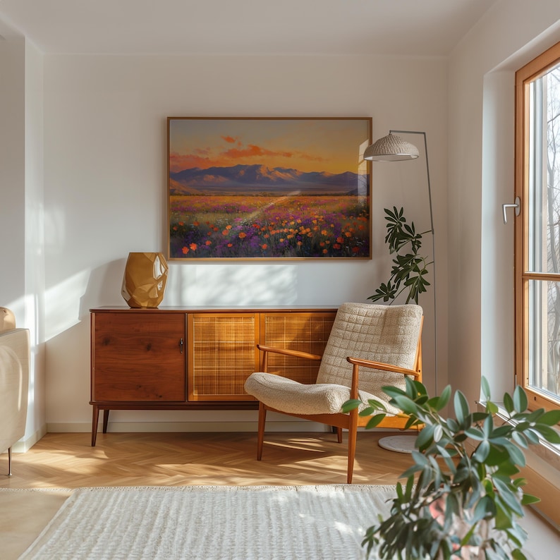 May include: A living room scene featuring a wooden cabinet, a beige armchair, and a framed landscape painting. The painting depicts a field of colorful flowers under a sunset sky. A gold vase and a floor lamp are also visible.