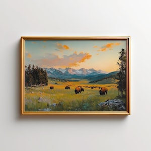 May include: A framed landscape painting shows bison grazing in a field, with mountains in the background. The sky is a mix of orange, yellow, and blue. The painting is in a gold frame.