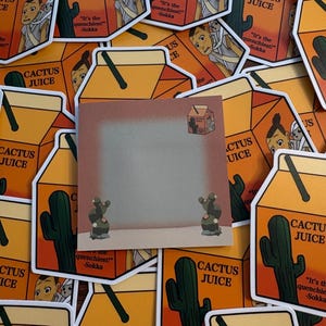 May include: A square memo pad featuring a gradient brown background, a small illustration of a Cactus Juice carton in the top right corner, and two small green cacti at the bottom, layered over multiple Cactus Juice carton stickers.