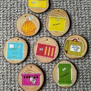 May include: Eight wooden round ornaments with different images of boxes, crates, and baskets. Each ornament has a tag that says "From the Zoo".