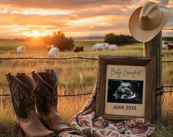 May include: A rustic wooden frame with a black and white ultrasound image inside. The frame is sitting on a colorful blanket with a cowboy hat and boots in the background. The text on the frame reads "Baby Crawford June 2025".
