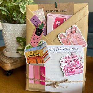 May include: A wrapped gift with a reading theme. The package is wrapped in brown paper and tied with twine. It is decorated with stickers that say "I'd rather be reading" and "Books are my love language". A tag reads "Reading List".
