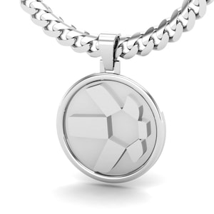 Puede incluir: Un collar de cadena de plata con un colgante redondo con un diseño geométrico.