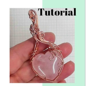 May include: A copper-colored wire-wrapped pendant with a heart-shaped rose quartz stone. The pendant is held in a hand, with the word "Tutorial" at the top and "KEY TO MY HEART" at the bottom.