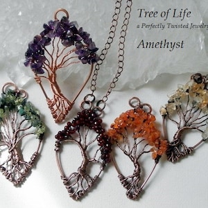 Pode incluir: Cinco pingentes de árvore da vida de fio de cobre com pedras preciosas de diferentes cores. Os pingentes estão dispostos em semicírculo sobre uma superfície branca. As pedras preciosas são ametista, aventurina verde, granada, cornalina e citrino. O texto "Tree of Life" e "Amethyst" é visível na imagem.