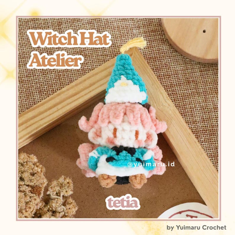 May include: A handmade crochet doll featuring a teal pointed witch hat with a white brim, light pink hair, and a teal and white outfit. The text Witch Hat Atelier and tetia are visible. The doll is crafted with soft yarn and intricate stitching.
