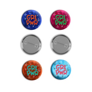 Può includere: Sei bottoni rotondi con retro argentato. Tre bottoni presentano uno sfondo blu con stelle bianche e il testo "GRL PWR" in arancione. Tre bottoni presentano uno sfondo rosso con stelle bianche e il testo "GRL PWR" in verde.