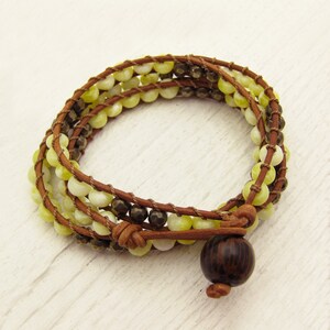 May include: A brown leather wrap bracelet with yellow and brown beads and a dark wood bead accent.