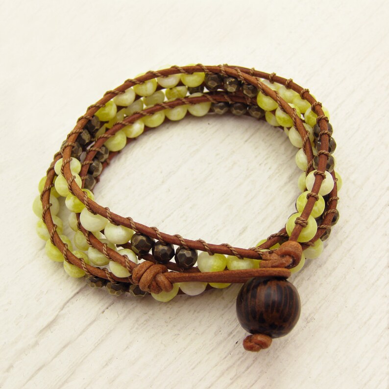 May include: A brown leather wrap bracelet with yellow and brown beads and a dark wood bead accent.