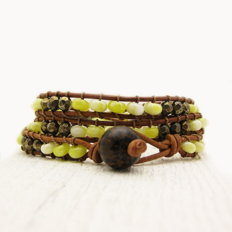 May include: A multi-strand leather wrap bracelet with yellow and white beads and a brown wooden bead accent.