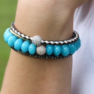 Puede incluir: Un brazalete con cuentas turquesa y blancas y dos acentos plateados y de diamantes.