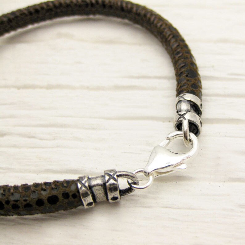 May include: A brown leather bracelet with silver accents and a silver clasp.