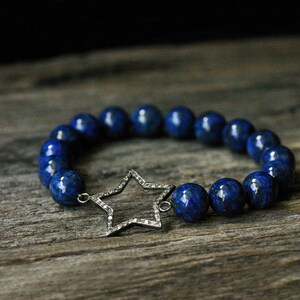 May include: A blue lapis lazuli beaded bracelet with a silver star charm. The star is set with small diamonds.