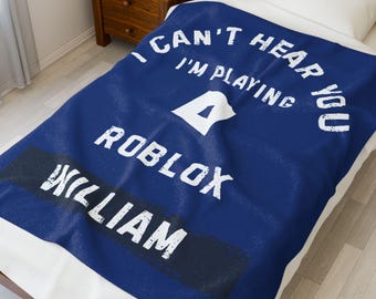 May include: A blue blanket with white text that reads "I CAN'T HEAR YOU I'M PLAYING ROBLOX WILLIAM". The blanket features a white triangle and a black rectangle with the name "WILLIAM".
