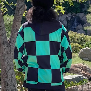 Puede incluir: Una sudadera con capucha a cuadros negros y verdes. La sudadera est&aacute; hecha de un material suave y c&oacute;modo y tiene un corte holgado.