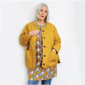 May include: A mustard yellow quilted jacket with a stand-up collar and button closure. The jacket has two patch pockets and a geometric patterned lining.