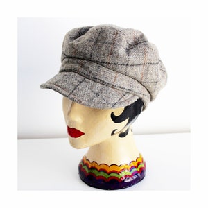 May include: A grey and brown checked newsboy cap with a slightly rounded crown and a short brim.