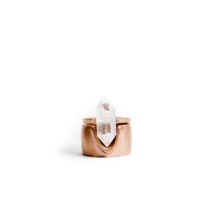 May include: A gold ring with a clear quartz crystal set in the center. The ring is designed to hold the crystal in place.