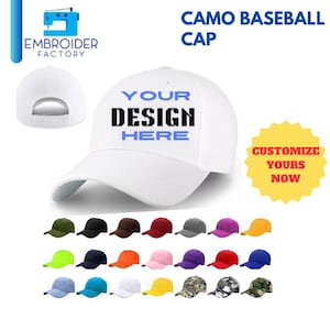 Op de afbeelding: Witte baseballpet met de tekst "YOUR DESIGN HERE" in blauw. De pet wordt getoond in verschillende kleuren, waaronder groen, rood, blauw, geel en camouflage.
