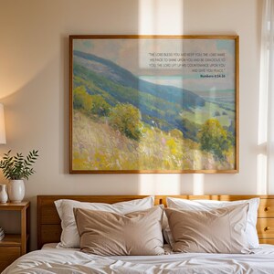 Könnte beinhalten: Ein Schlafzimmer mit einem Holzbettgestell, weißen Bettwäsche und zwei braunen Kissen. Ein gerahmtes Gemälde mit einer Landschaftsszene und einem Bibelvers hängt über dem Bett. Ein Nachttisch aus Holz mit einer Lampe und einer kleinen Pflanze steht neben dem Bett.