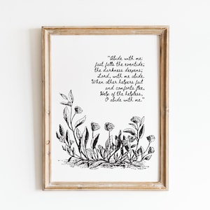 Op de afbeelding: Een ingelijste print met een lichtbruine houten lijst. De print toont een zwart-wit botanische illustratie aan de onderkant en de tekst die luidt "Abide with me: fast falls the eventide; the darkness deepens; Lord, with me abide..."