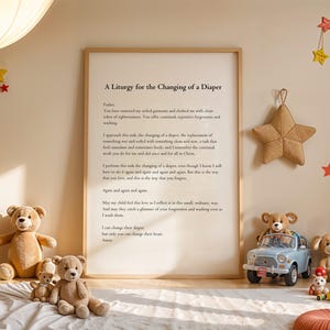 May include: A framed print with a poem titled "A Liturgy for the Changing of a Diaper." The poem is about the act of changing a diaper and the love and forgiveness that goes into it. The print is surrounded by stuffed animals and toy cars, creating a nursery-themed scene.