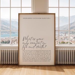 May include: A framed print with the text "HEIDELBERG CATECHISM QUESTION I" at the top. Below, the text reads "What is your only comfort in life and death?" and a longer passage. The print is in a light-colored wooden frame.