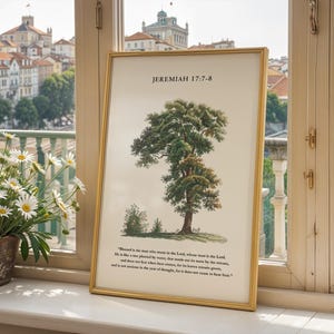 May include: A framed print with a gold frame and a watercolor illustration of a tree. The print includes the text "Jeremiah 17:7-8" and a quote from the Bible: "Blessed is the one who trusts in the Lord, whose trust is the Lord. He is like a tree planted by water, that sends out its roots by the stream, and does not fear when heat comes, because its leaves remain green, and it is not anxious in the year of drought, for it does not cease to bear fruit."