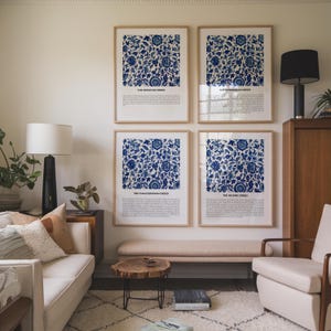 May include: Four framed art prints with a blue and white floral pattern. Each print has text at the bottom. The prints are displayed in a living room setting with a sofa, chair, and wooden furniture.