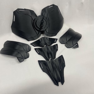 Könnte beinhalten: Ein Satz schwarzer Plastik-Kostüm-Rüstungsteile. Die Teile umfassen eine Brustplatte, Schulterpolster und ein paar kleinere Teile.