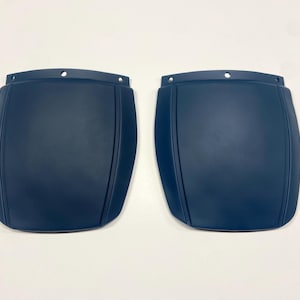May include: Two dark blue, slightly curved, plastic panels with a smooth, matte finish. The panels have a slight indentation in the center and are designed to be attached to a surface.