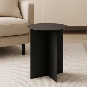 Könnte beinhalten: Ein moderner schwarzer Beistelltisch mit runder Tischplatte und geometrischem Fuß. Der Tisch besteht aus massivem Material und steht auf einem neutralfarbenen Teppich. Das Design ist minimalistisch und für verschiedene Einrichtungsstile geeignet.