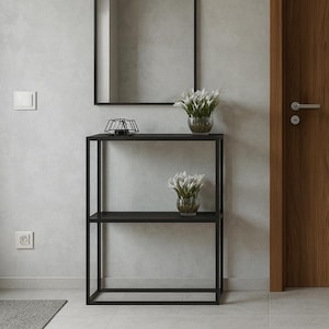 Pode incluir: Uma entrada moderna com uma consola de metal preto, um espelho retangular e uma porta de madeira. O espaço é decorado com flores brancas em vasos e uma planta em vaso. Um tapete cinzento e um par de sapatos castanhos completam a cena.