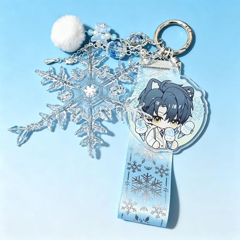 May include: A clear snowflake keychain with a silver chain, a white pom-pom, and a blue ribbon with snowflake designs. The keychain also features a cartoon character with blue hair and cat ears holding ice cream cones.