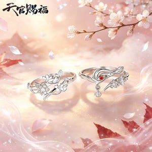 May include: Two silver rings with floral and butterfly designs. One ring features a red gemstone and a dangling charm. The rings are set against a soft pink background with cherry blossom accents. The Chinese characters "六官赐福" are at the top.