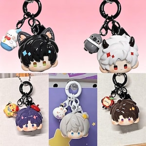 May include: Collection of anime-style keychains featuring various characters with different hair colors and accessories. Each keychain has a black ring and a small charm. The characters have cute facial expressions and are in a cartoon style.