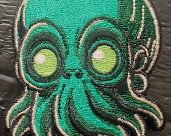 Op de afbeelding: Groene geborduurde patch van een cartoon octopus met grote ogen en tentakels.