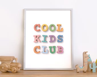 May include: A white framed print with the words "COOL KIDS CLUB" in colorful letters. The letters are arranged in a staggered pattern and are made of different colors, including pink, blue, yellow, and orange.