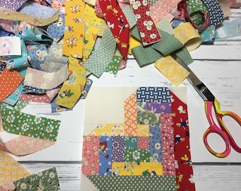 May include: A colorful patchwork heart quilt block made from scraps of fabric with a variety of floral and geometric patterns. The block is surrounded by strips of fabric in various colors and patterns.