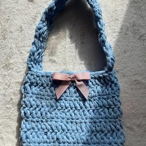 May include: A white ceramic mug with a black handle and the text "But First, Coffee" in a bold, black font. The mug is set against a blurred background, suggesting a cosy setting.