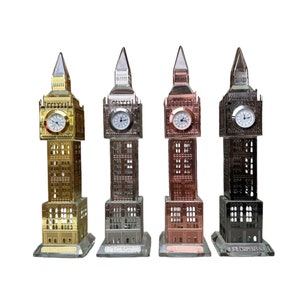 May include: Four miniature Big Ben clock tower replicas in different metallic finishes: gold, silver, copper, and black. Each replica has a clear glass base with the inscription "Big Ben, London".