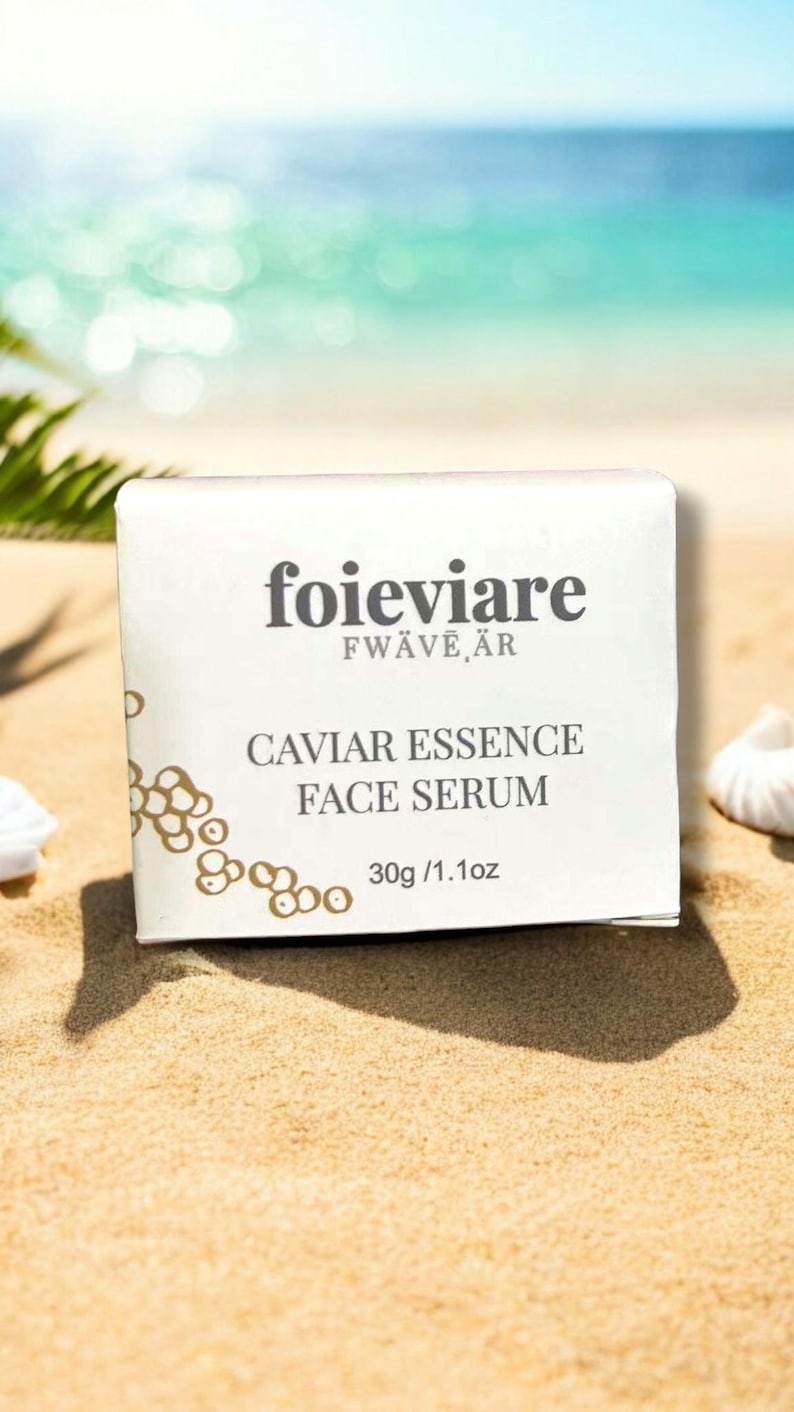 Może przedstawiać: Białe pudełko z nadrukowanym tekstem "foieviare FW&Auml;VE,&Auml;R" i "CAVIAR ESSENCE FACE SERUM 30g / 1.1oz". Pudełko leży na piaszczystej plaży.