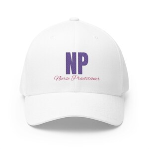 May include: A white baseball cap featuring the purple letters NP in a bold, textured font centered on the front. Below the letters, the words Nurse Practitioner are printed in a smaller, cursive pink script font on the white fabric surface.