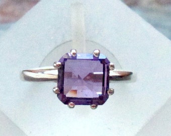 May include: A silver ring with a square, purple amethyst gemstone.